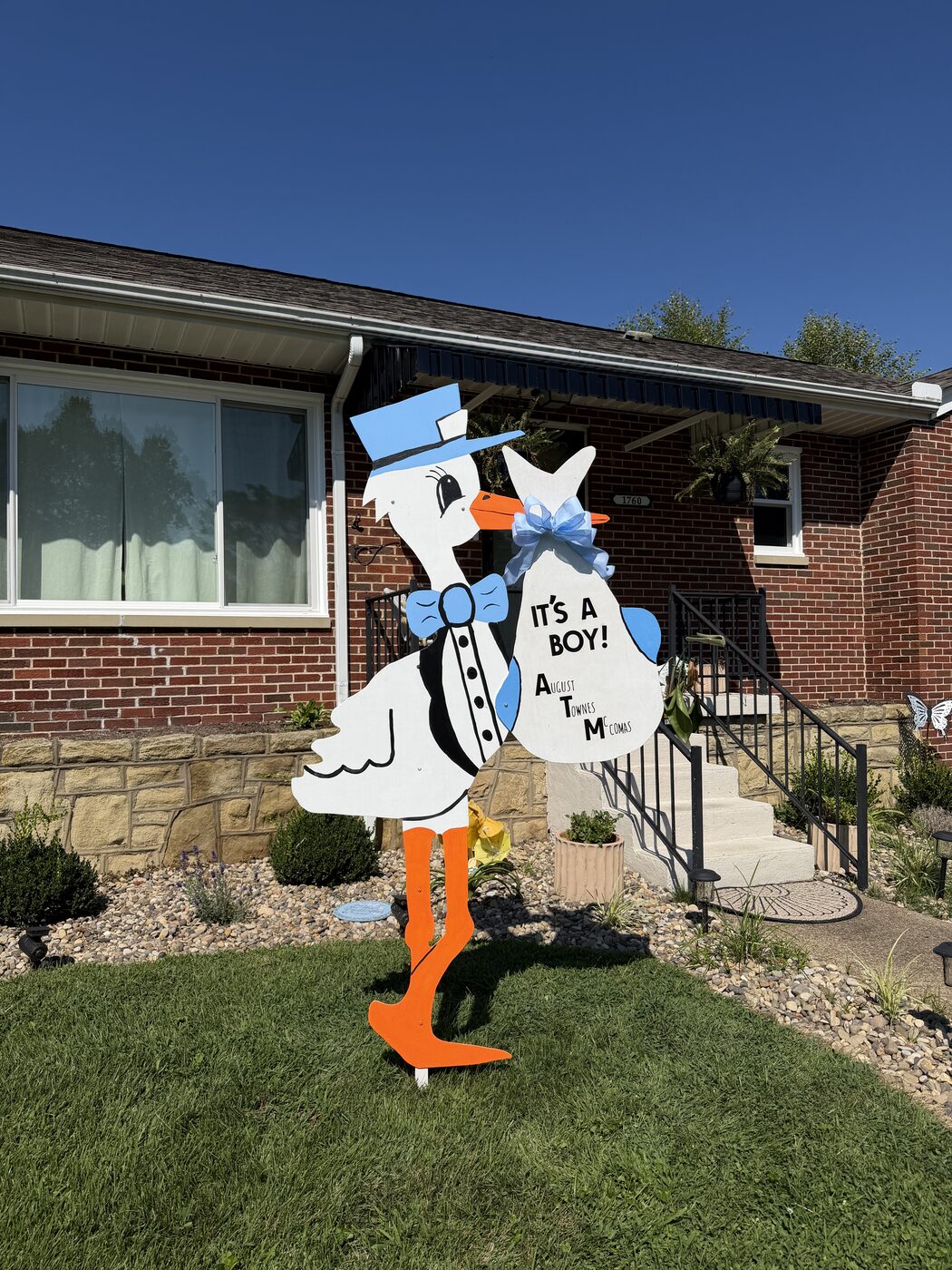 Blue stork sign reading It's a Boy, August Townes McComas, in a front yard.