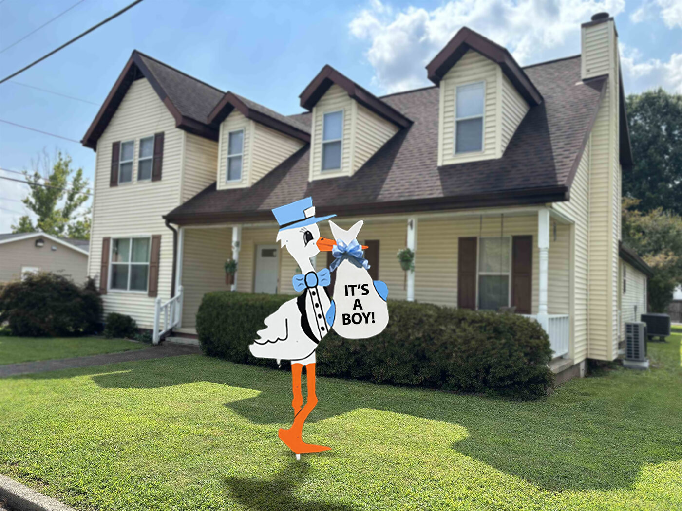 Blue stork sign reading It's a Boy in a front yard.